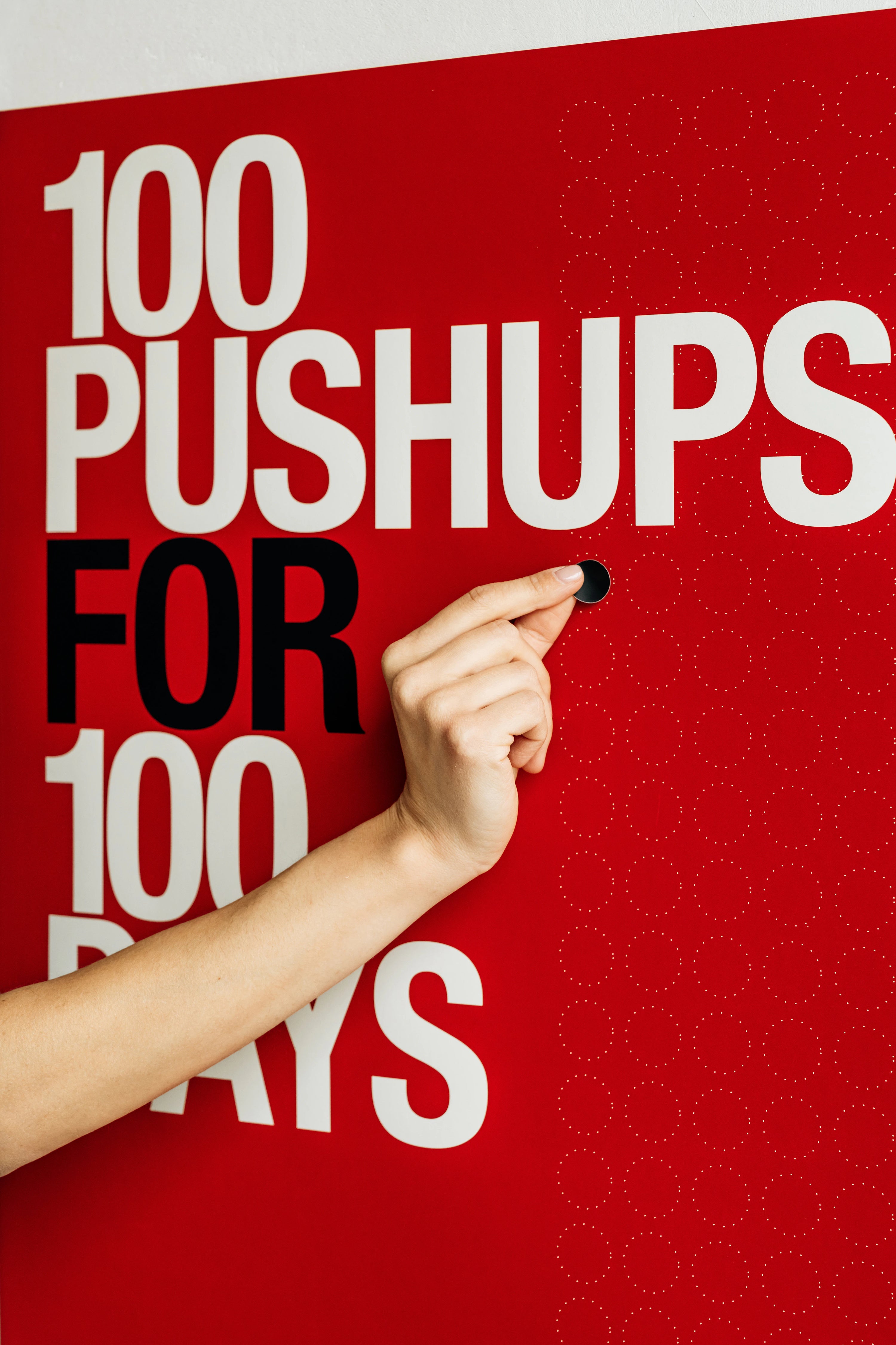 Hand pointing to '100 Pushups for 100 Days' on a red background