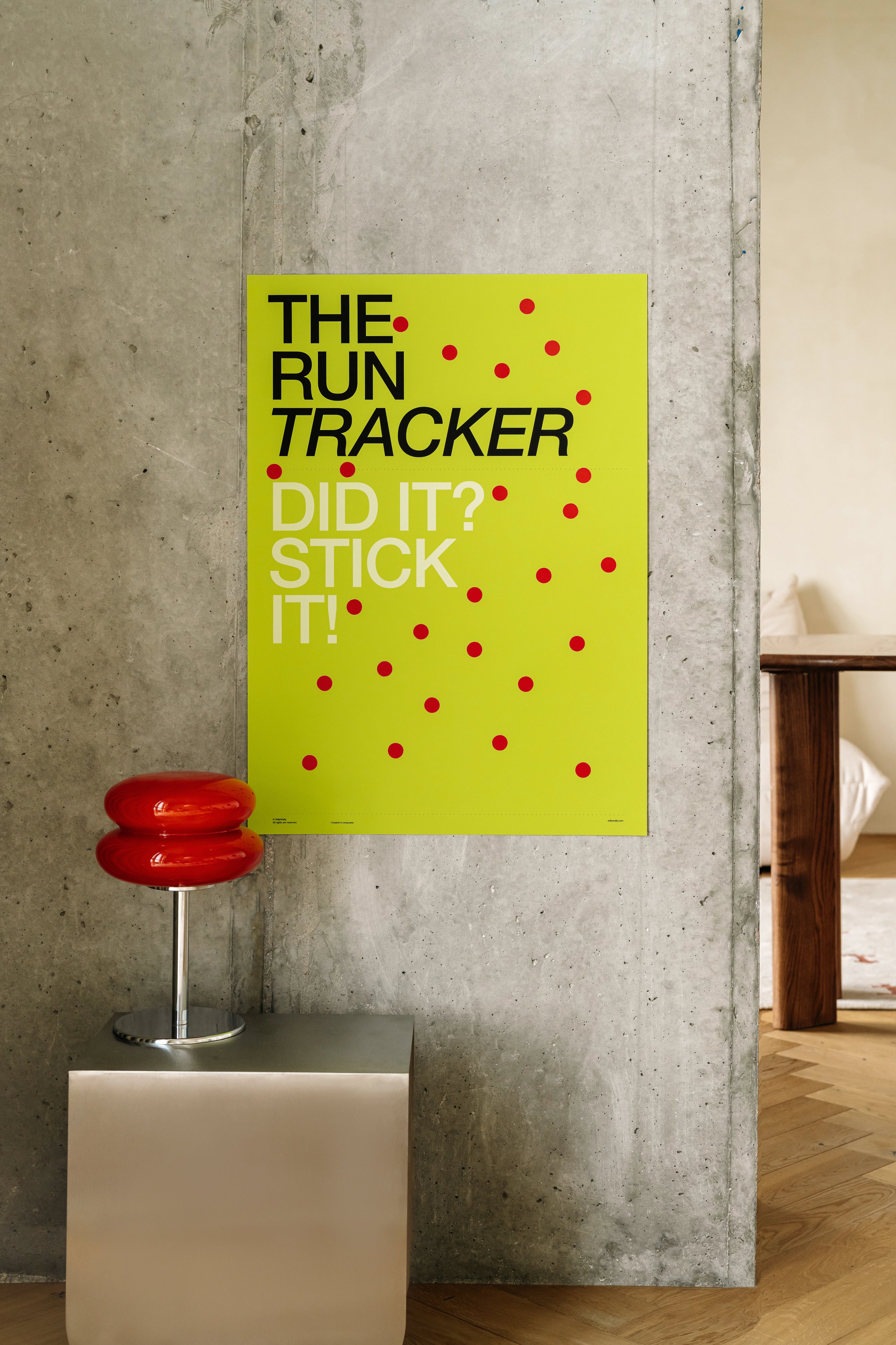 Poster titled 'The Run Tracker' with text and red dots on a yellow background, leaning against a textured wall.