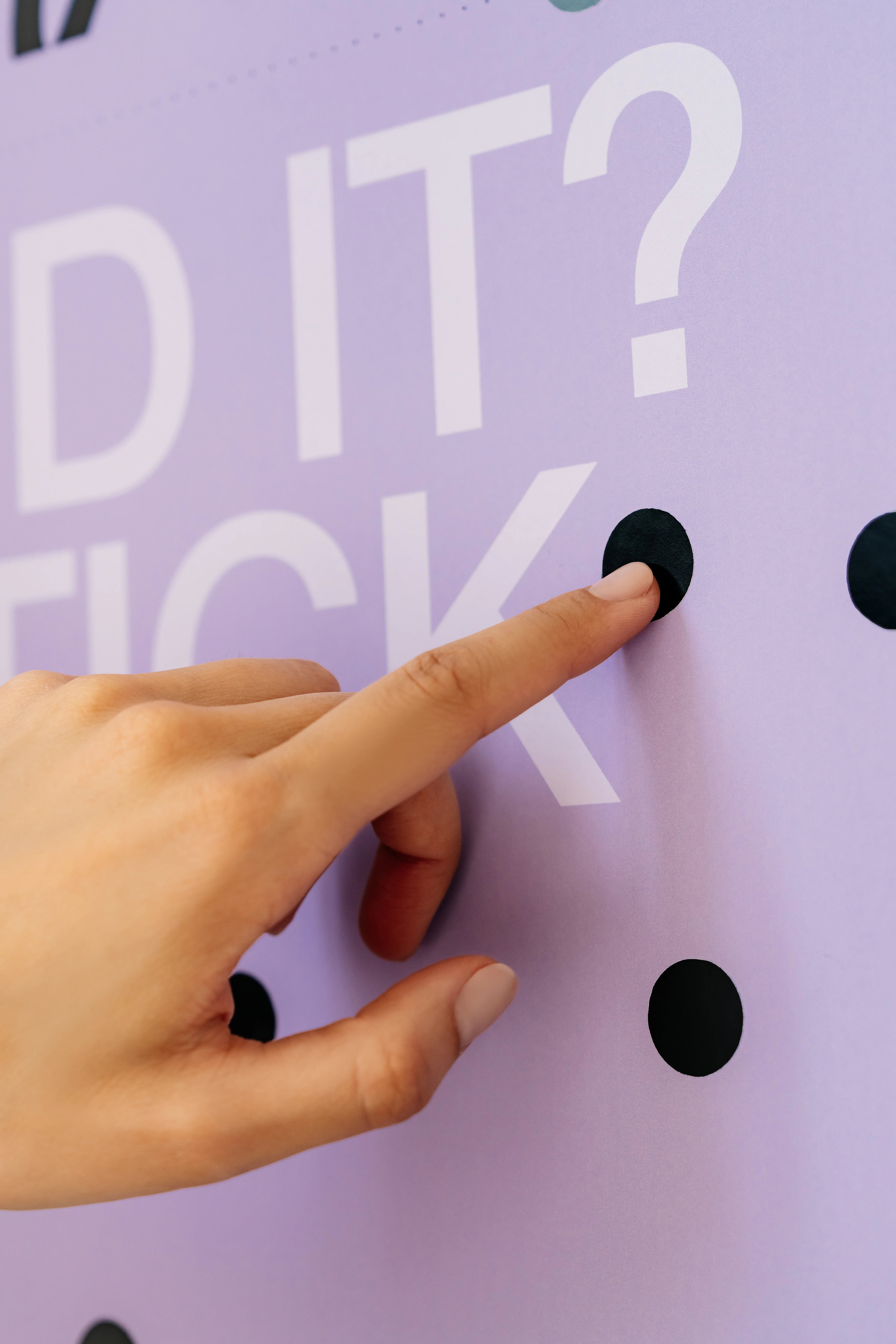 Hand pointing to a question mark on a purple background with text.