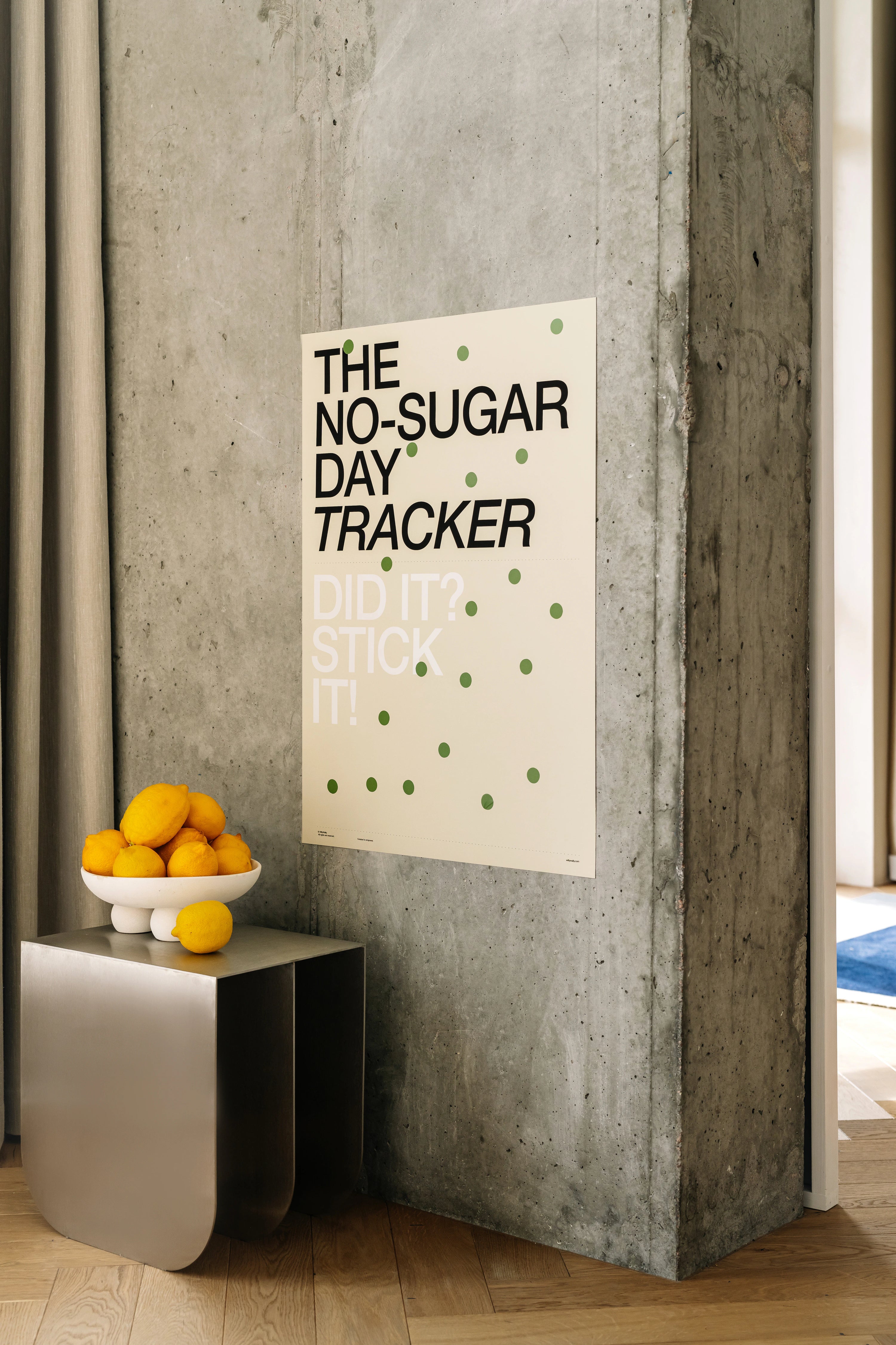 No-Sugar Day Tracker poster on a concrete wall with oranges on a small table.