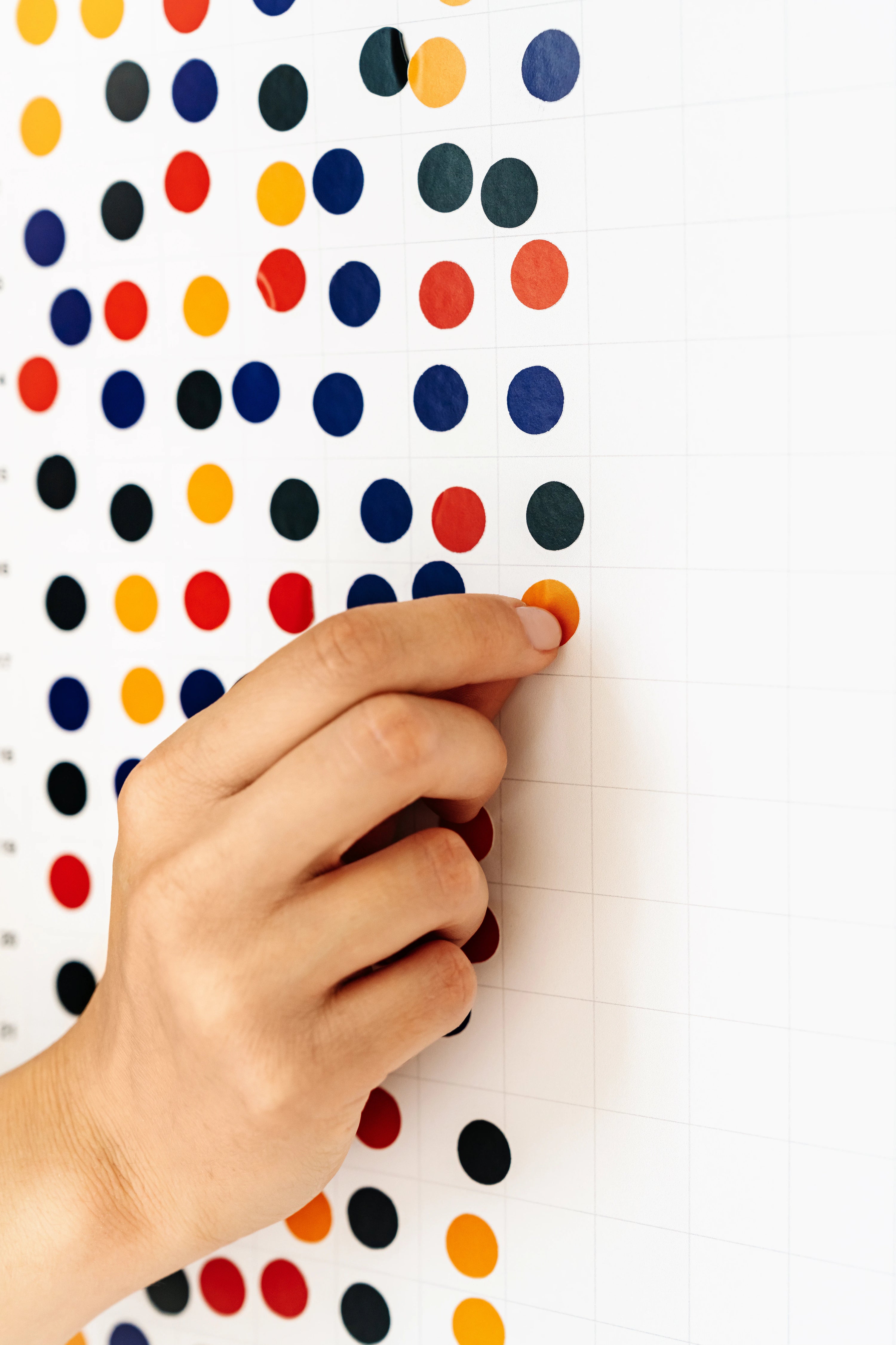 Hand holding a pencil against a background with colorful polka dots